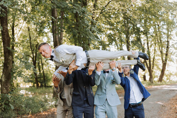 A group of friends lifts the happy groom to the top, the company of the groom's friends celebrate...