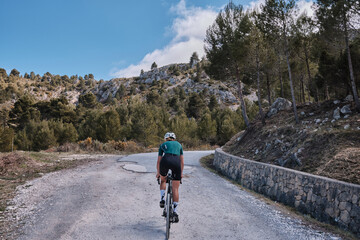 Close up back view of a female cyclist during ride.Woman cyclist wearing cycling kit and helmet...