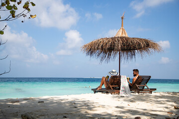 couple relaxing on tropical beach chairs