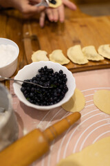 sculpt dumplings with blueberries. Cooking homemade blueberry dumplings. Ready dumplings, a piece of dough stuffed with berries and a colander with blueberries