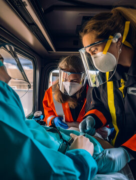 Female paramedics in protective masks and shields helping the patient. Medics saving life in the ambulance car. Generative AI.