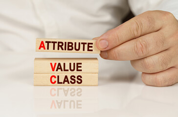 In the hands of a person and on a reflective surface are wooden blocks with the inscription -...