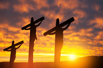 Silhouette of the crucified Jesus Christ on the cross along with other people on background of...