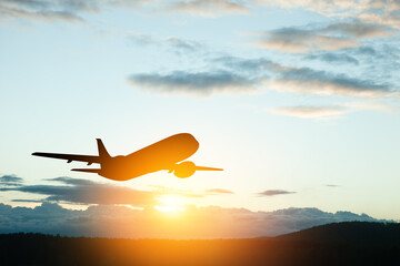 Airplane taking off at the sunset sky. Silhouette of aircraft in the sky.
