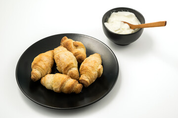 Traditional rolled dough called Kiflice served wuth yogurt on black plate and white background