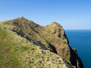 Kallur lighthouse at the end of the hiking path, by the cliffs edge of north Kalsoy