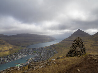 A cairn on top of Klakkur mountain hiking path, with Klaksvik below in the horizon - Powered by Adobe