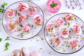 Różowe jajka barwione sokiem z buraka faszerowane nadzieniem chrzanowym z rzodkiewką, kiełkami i szczypiorkiem. Wielkanocna potrawa z jajek.
