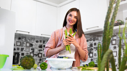 A Young smiling beautiful woman holding romano helda green beans in hands. The concept of a healthy nutrition and vegetarian diet food. Lifestyle and emotions. Copy space