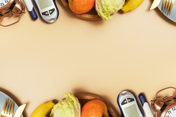 Glucose meter with cutlery and alarm clock on beige background with copy space flat lay, top view