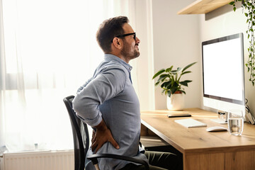A remote worker is having back pain while sitting at his home office.