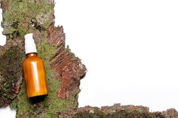 Glass dropper brown bottle with cosmetic oil, cream, essential or serum on bark tree and green moss. Concept of natural organic eco spa cosmetics. Herbal homeopathic products, copy space