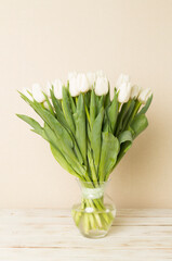 White tulip flowers in vase on wooden table