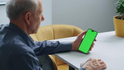 Elderly Man Calling By Video Call By Smartphone, Sitting Alone At Home, Green Screen On Gadget