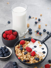 Tasty granola with berries and yogurt on stone background, close up. Healthy breakfast.