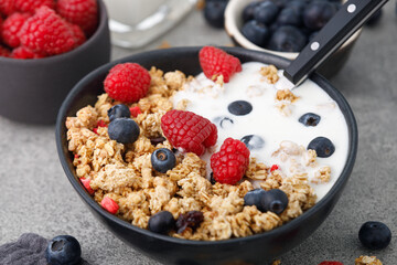 Cereal with berries and yogurt on stone background, close up. Healthy breakfast.