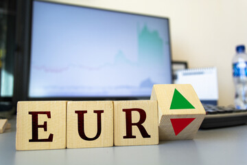 Wooden cubes with the inscription EUR and a cube symbolizing the rise and fall of financial markets.