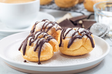 Profiteroles with whipped cream and chocolate filling, covered with melted chocolate, horizontal