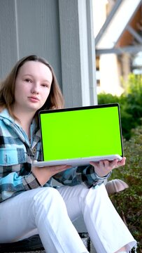 young pretty student woman bored tired over worked on her laptop wearing a black shirt isolated on green screen cromakey chormakey or chroma croma key for composite. High quality photo