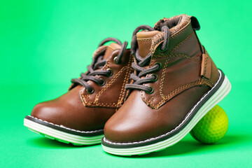 children's leather shoes with laces and a golf ball on a green background. Close-up.
