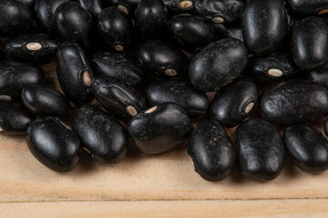 heap of black beans scattered over rustic wood