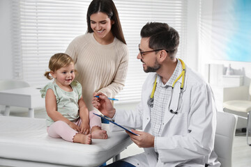 Mother and her cute baby having appointment with pediatrician in clinic. Doctor examining little...