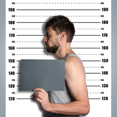Criminal mugshot. Arrested man with blank card against height chart