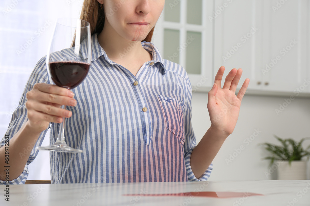 Wall mural Woman with wine stain on her shirt at white marble table indoors, closeup