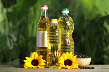 Bottles of cooking oil, sunflowers and seeds on wooden table against blurred background