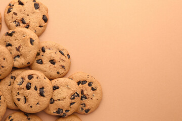 Many delicious chocolate chip cookies on beige background, flat lay. Space for text