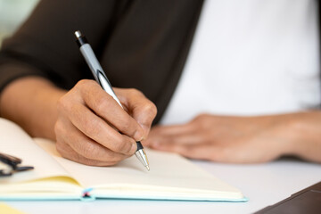 Student studying, exam preparation,  holding pen taking notes in diary, selective focus. Close up of business woman hand writing, working with document in office 