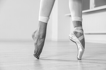 Ballerina in pointe shoe dancing indoors, closeup. Black and white effect