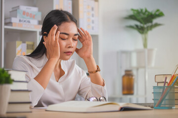 Young woman keeping eyes closed and massaging nose while sitting at her working place in home office. Unhappy woman with headache using laptop while sitting at table.