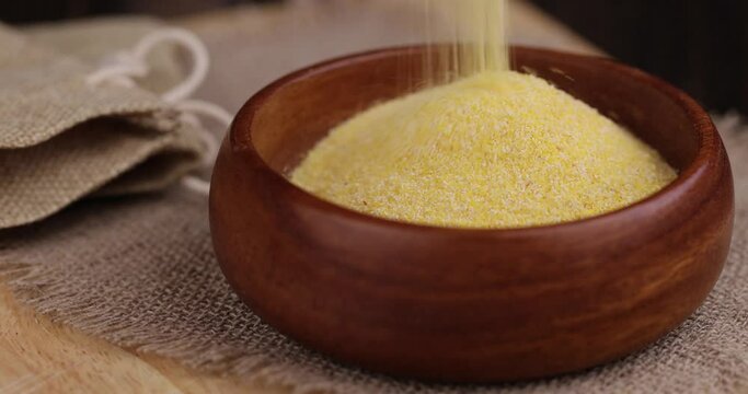 pour in Round wooden bowl with dry corn flour for cooking porridge, high-quality corn flour from corn grains in a bowl for a studio