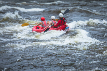 Raft boat during whitewater rafting extreme water sports on water rapids, kayaking and canoeing on the river, water sports team with a big splash of water, 3 persons in a raft boat