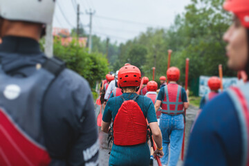 Group of sportsmen in wetsuits with paddles in helmets and life jackets vest prepare to extreme water sports, team before rafting, kayaking, canoeing in a summer day, equipment view with raft boat