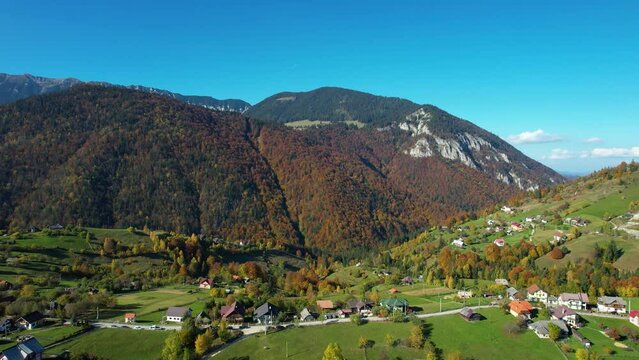 Aerial View Of A Small, Pittoresque And Isolated Mountain Village In Autumn With Green Hills And Trees With Colorful Leaves, Impressive Mountain Peaks And A Clear Blue Sky, Magura, Zarnesti, Romania