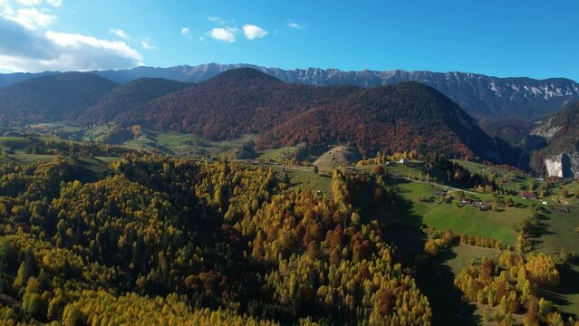 Captivating Autumn Scenery A Serene Mountain Village nestled in the Majestic Magura, Zarnesti, Romania - Breathtaking Aerial Views of Lush Green Hills, Trees adorned in Vibrant Hues, and Majestic Peak