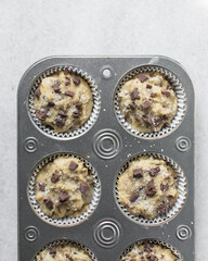 Fototapeta na wymiar Chocolate chip muffin batter in a lined cupcake tin, vanilla and chocolate chip muffin batter, process of making muffins