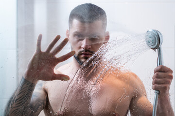 Portrait of naked man taking shower in bathroom. Male hygiene routine. Sexy man with wet muscular body washing in the shower. Guy in the shower bath. Man taking hot shower. Morning routine.