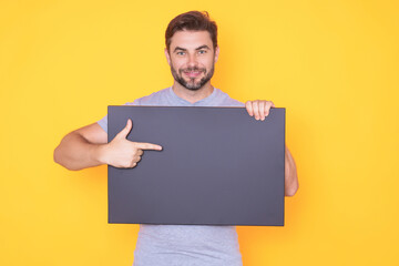 Man in studio showing promo blank board pointing finger on sign board. Blank signboard with copyspace. Advertisement concept. Ad board with copy space, blank mockup. Blank signboard, placard.