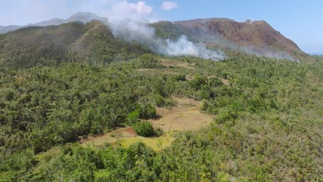 Aerial flyover CABO CABRON NATIONAL PARK with dangerous forest fire during sunny day