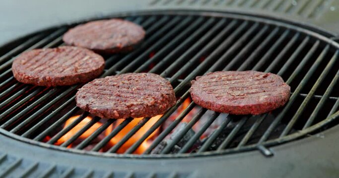 shot of tasty vegan burgers cooking on hot flaming open outdoor BBQ grill