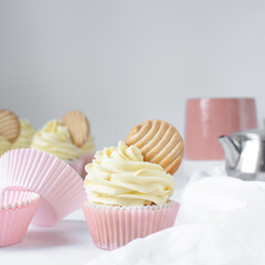 Pink cupcakes with tall american buttercream swirl and cookie garnish, cupcakes in pink liners with a tall vanilla buttercream and a cookie, birthday cupcakes on a white background