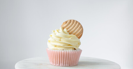 Pink cupcakes with tall american buttercream swirl and cookie garnish, cupcakes in pink liners with a tall vanilla buttercream and a cookie, birthday cupcakes on a white background