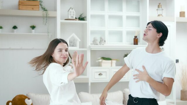 Happy young couple dancing and laughing having fun celebrate at house in living room