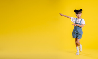 image full body of asian little girl posing on a yellow background