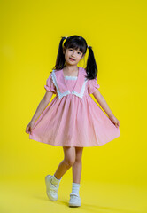 image full body of  asian little girl posing on a yellow background