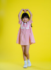 image full body of  asian little girl posing on a yellow background