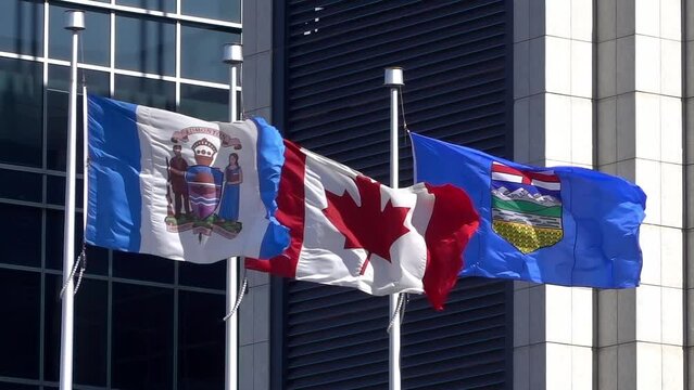 A flag of the City of Edmonton with a Canadian flag and an Alberta flag waving in slow-motion.